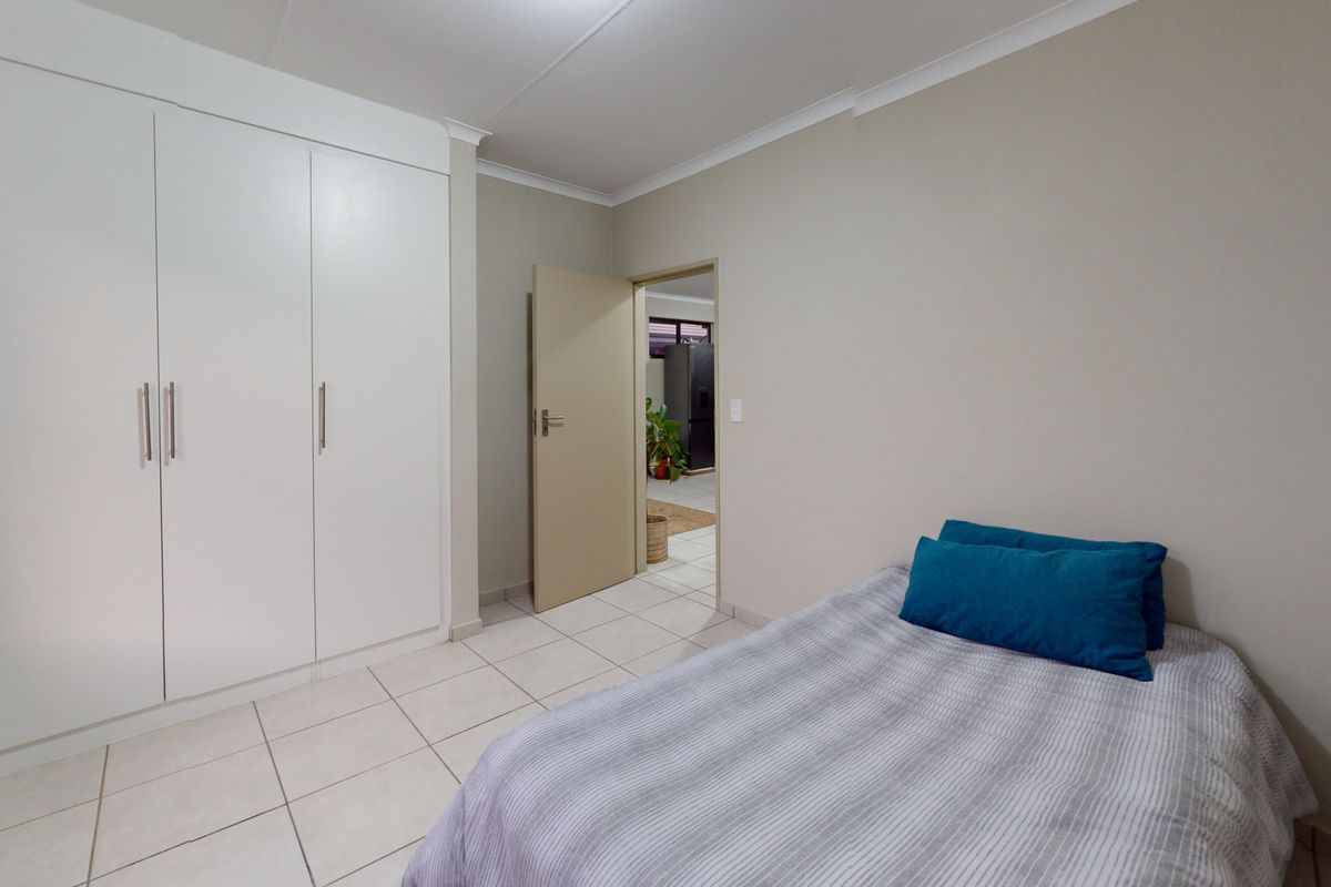 A clean bedroom featuring neutral walls, tiled flooring, and ample built-in cupboard storage space.