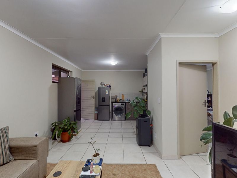 Open-plan living area featuring tiled flooring and a functional kitchen space with built-in cabinetry and sink.