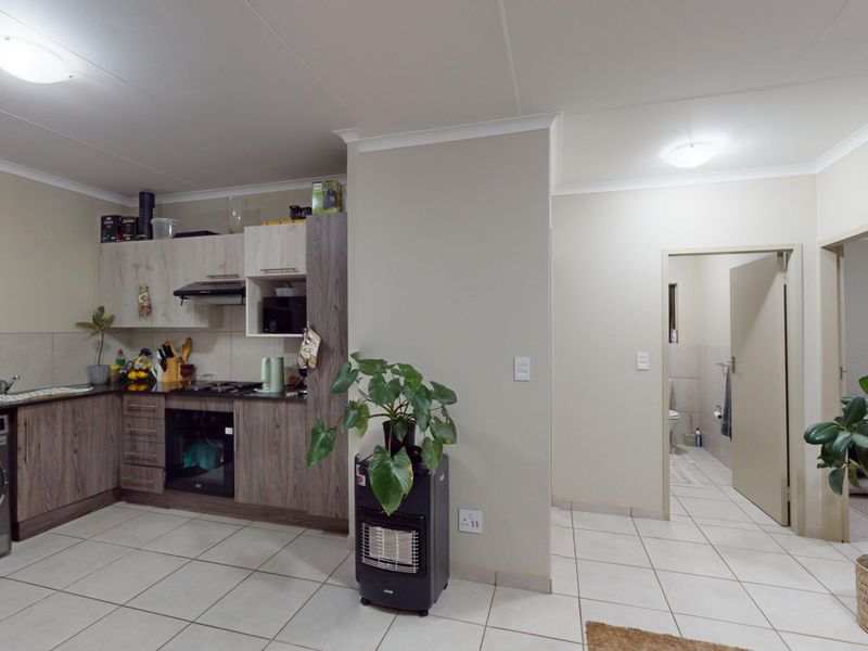 Open plan kitchen area featuring modern wood-look cabinetry, integrated oven, extractor fan, and tiled flooring, with direct access to adjacent rooms.