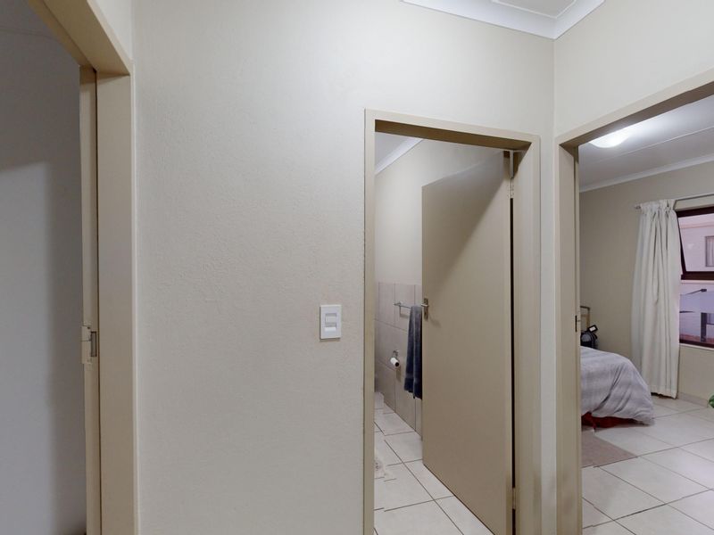A neutral-toned hallway providing access to multiple rooms, featuring tiled flooring and standard internal door frames.
