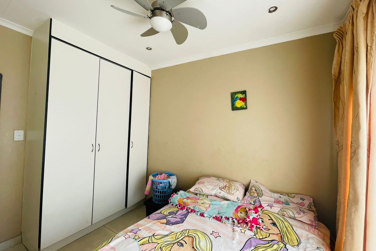 A bedroom featuring built-in white cabinetry, a ceiling fan, and tiled flooring.
