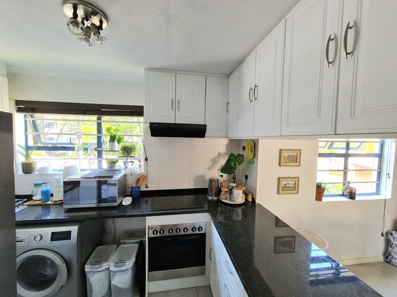 Functional kitchen featuring white cabinetry, dark granite countertops, built-in oven, electric hob, and an integrated space for a washing machine.