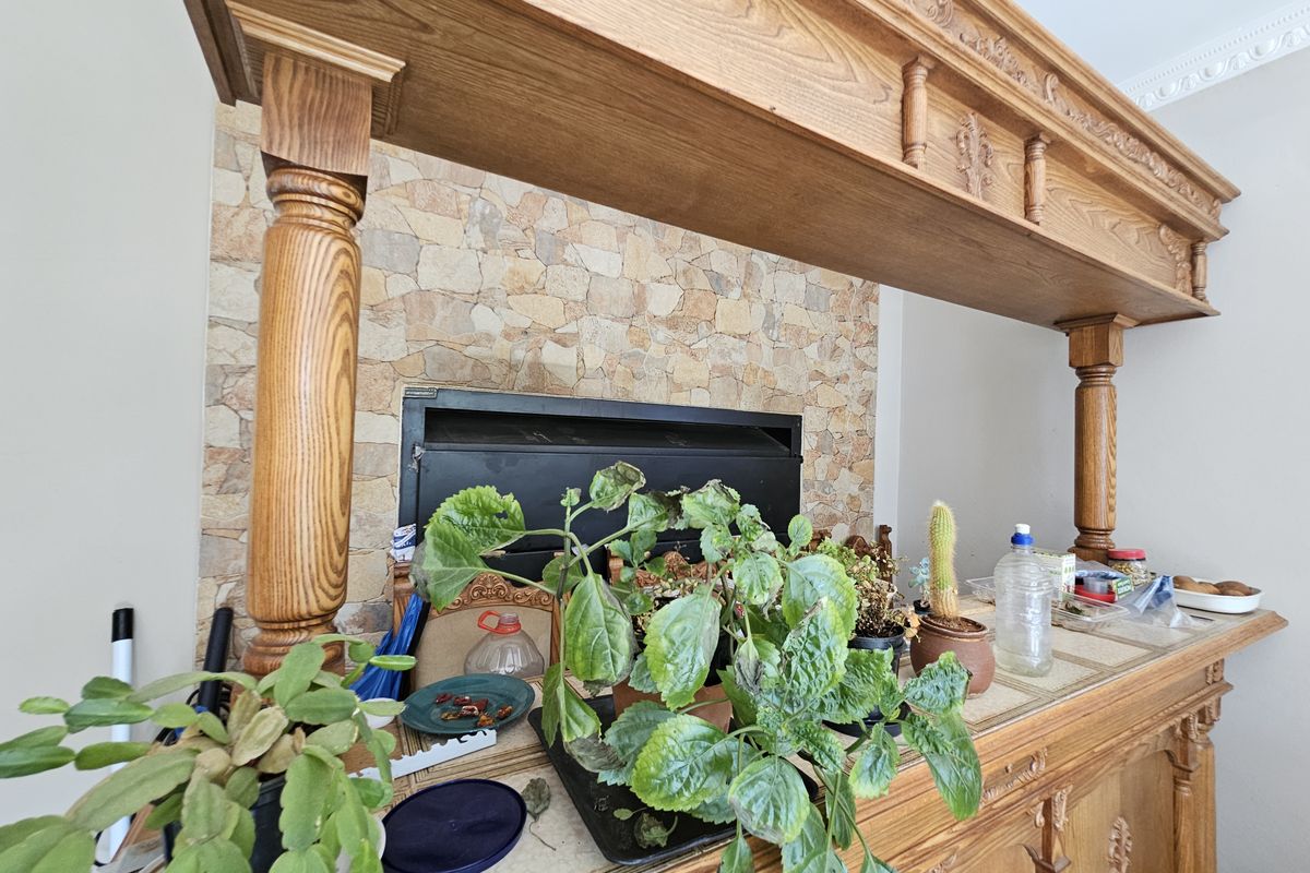 A living area featuring a prominent built-in fireplace with stone cladding and a decorative wooden mantelpiece with columns.