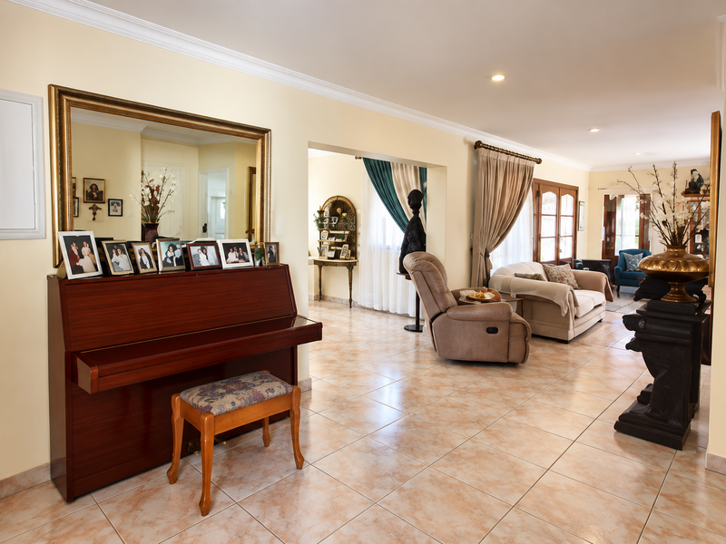 Spacious open-plan living area featuring neutral ceramic floor tiles, recessed lighting, and crown molding, creating a bright and connected flow between living spaces.