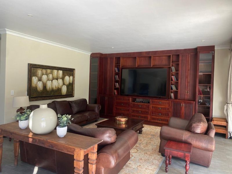 A spacious living room featuring extensive built-in wooden cabinetry and shelving, tiled flooring, and recessed ceiling lighting.
