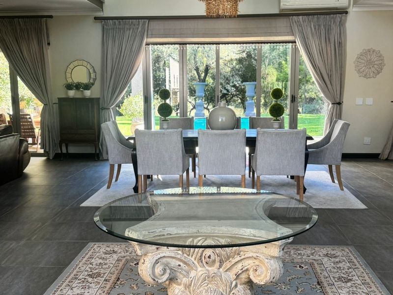 Spacious open-plan living and dining area featuring high ceilings, large glass sliding doors leading to the garden, and a modern mezzanine level.