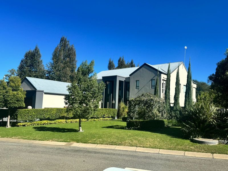 A well-maintained double-storey residential property featuring a modern facade, metal roofing, and a neatly landscaped front garden with established hedging.