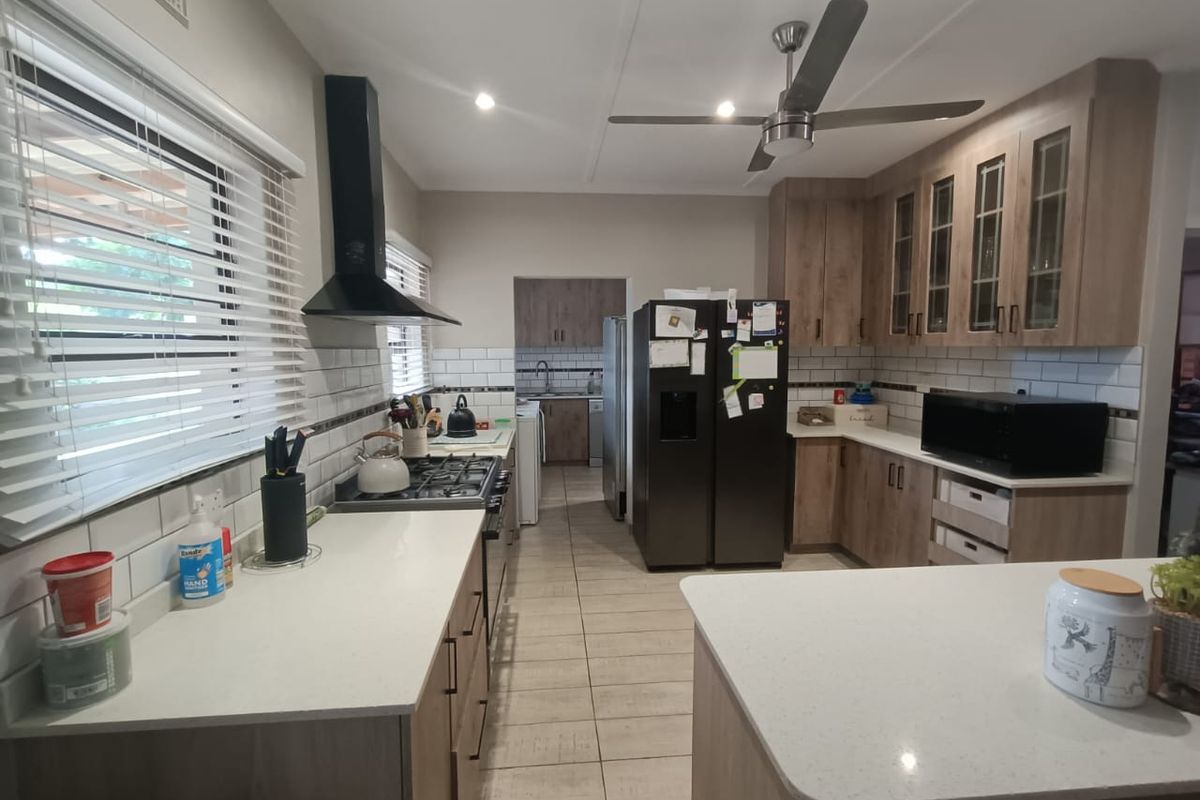 Modern kitchen featuring light wood cabinetry, stone countertops, subway tile backsplash, gas cooktop with extractor fan, and a functional scullery area.