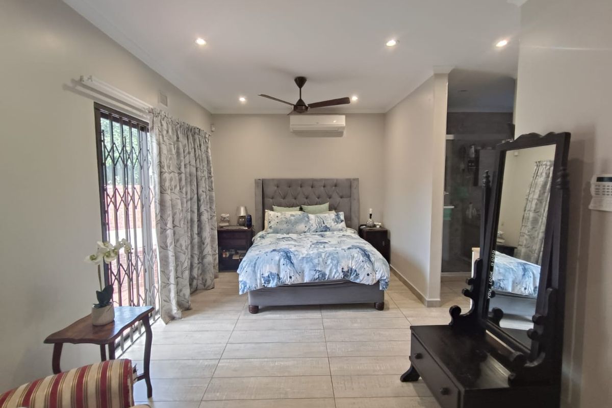 Spacious bedroom featuring tiled flooring, recessed lighting, a ceiling fan, split-system air conditioning, and direct access to an en-suite bathroom.