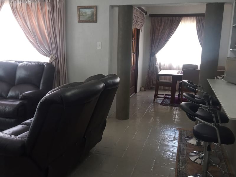 Open plan living and dining area featuring tiled flooring, structural columns, and a breakfast bar, offering a functional layout for daily living.