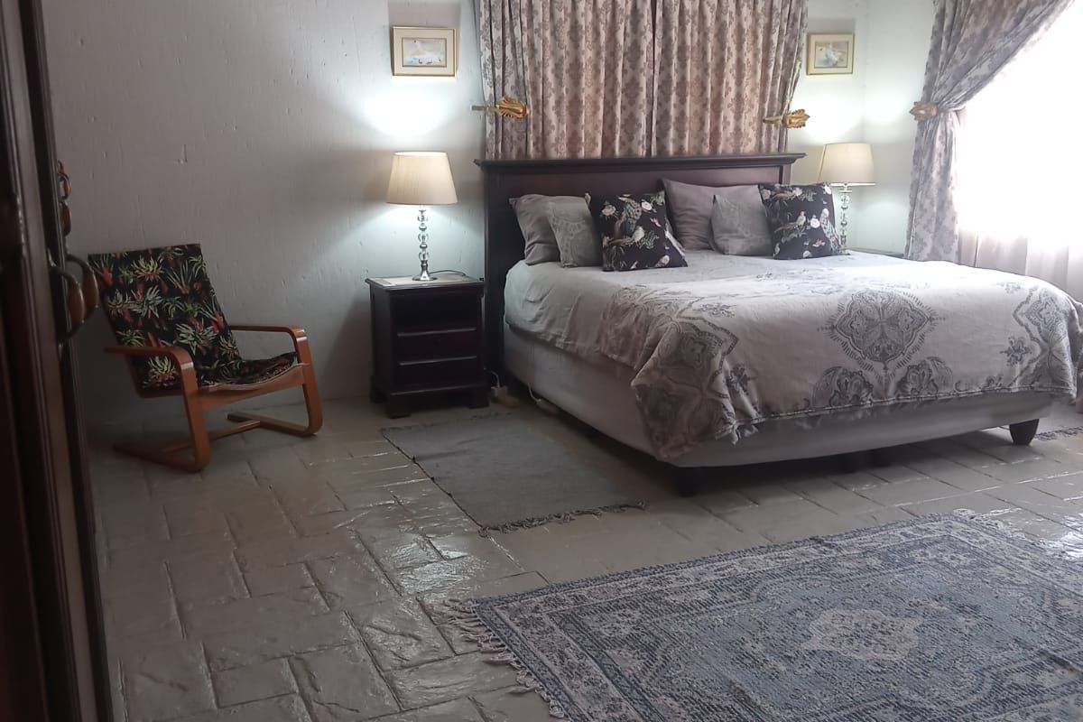 Spacious bedroom featuring textured tiled flooring and dual window treatments, offering a comfortable and functional sleeping area.