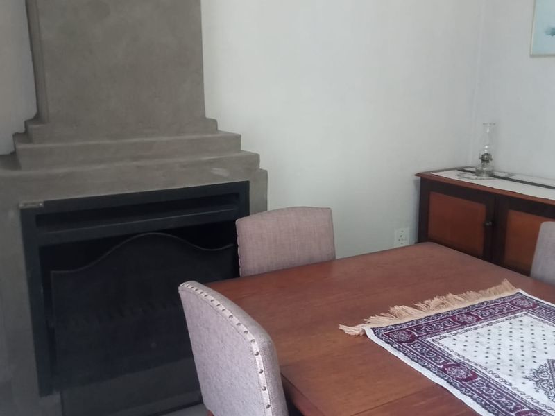 Dining room featuring a prominent built-in concrete fireplace and tiled flooring, providing a cozy and functional space for meals.