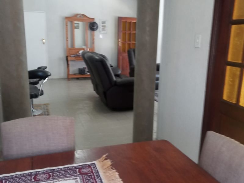 Open plan living area featuring structural columns and tiled flooring, connecting the dining space to the adjacent lounge area.