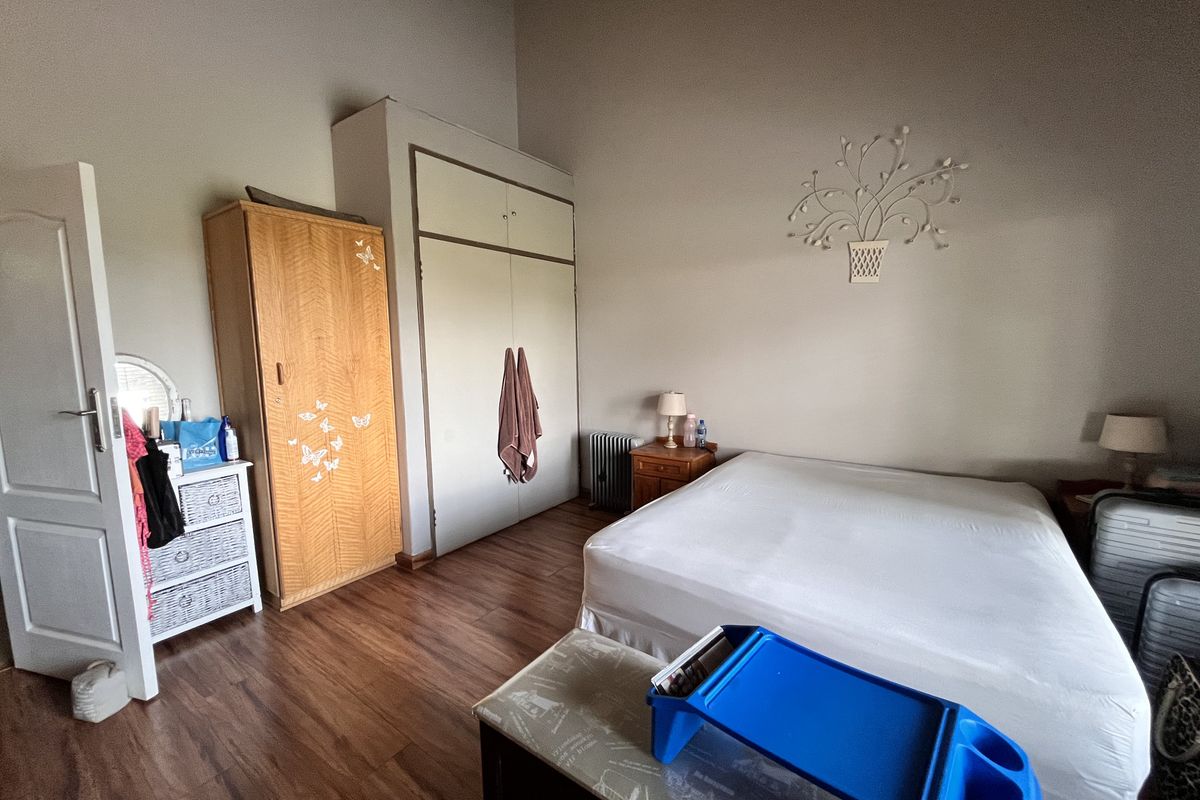 A bedroom featuring laminate flooring and built-in cupboards, offering a functional space with high ceilings.
