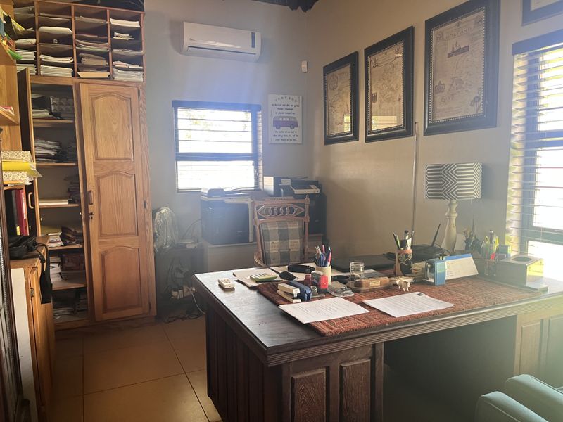 A functional home office featuring built-in wooden cabinetry, tiled flooring, and a wall-mounted air conditioning unit, providing a practical workspace.