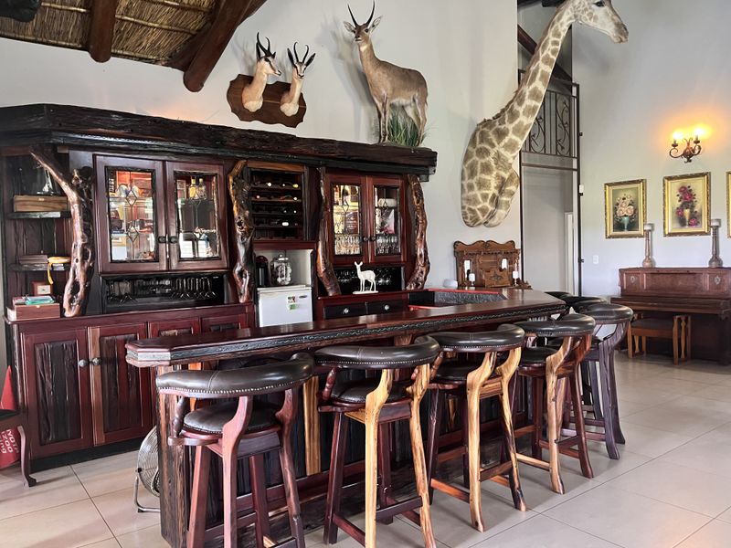 A rustic-style built-in bar area featuring custom dark wood cabinetry, a wine rack, and a thatched roof accent, creating a unique entertainment space.