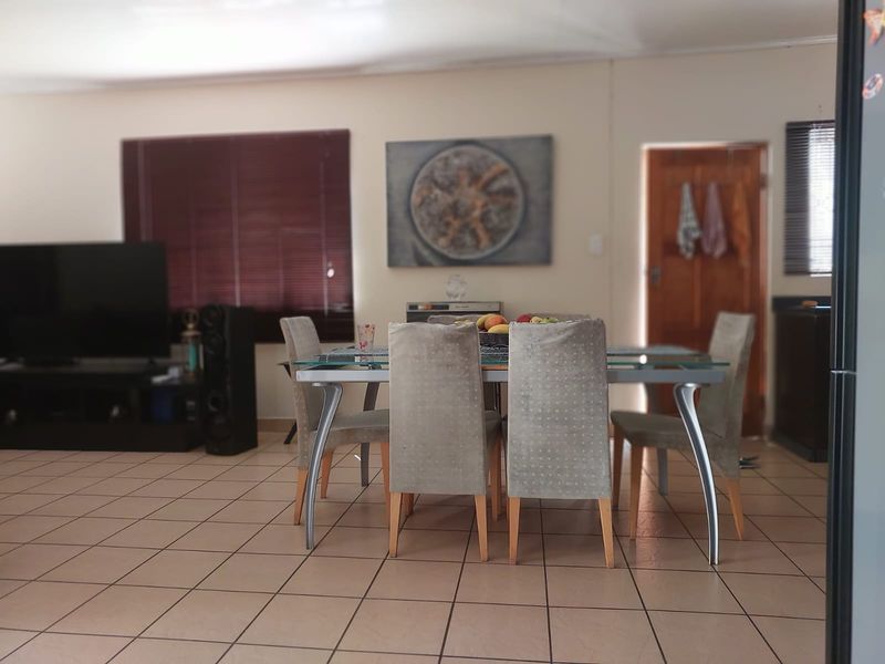 Open plan living and dining area featuring neutral tiled flooring and venetian blinds, providing a functional and versatile space for daily living.