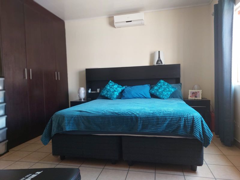 A bedroom featuring tiled flooring, built-in cupboards, and a wall-mounted split-system air conditioner.