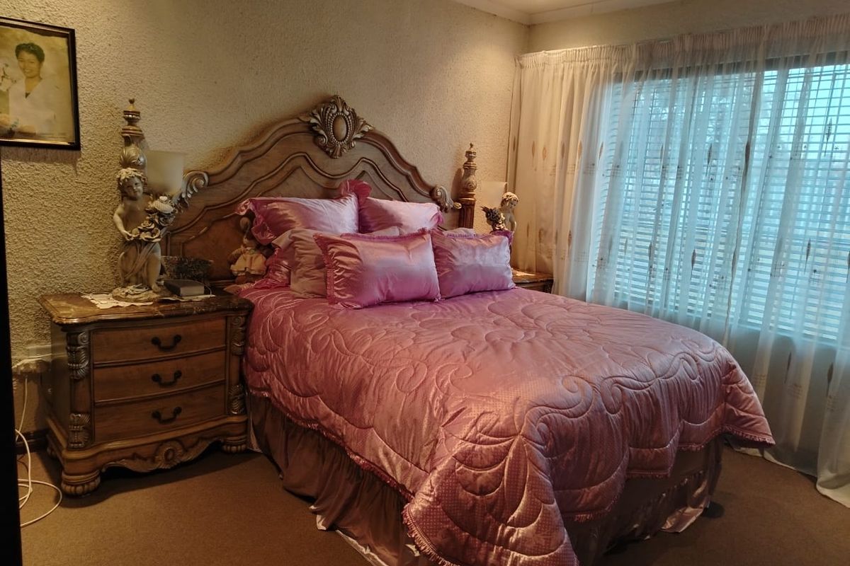A cozy bedroom featuring textured walls, recessed downlighting, and large windows with fitted curtain tracks, offering a comfortable and private sleeping space.