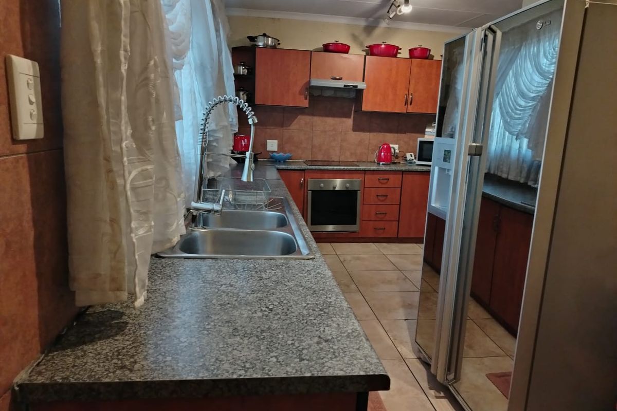 A functional kitchen featuring laminate cabinetry, granite countertops, a double sink with gooseneck faucet, and built-in oven with extractor fan.