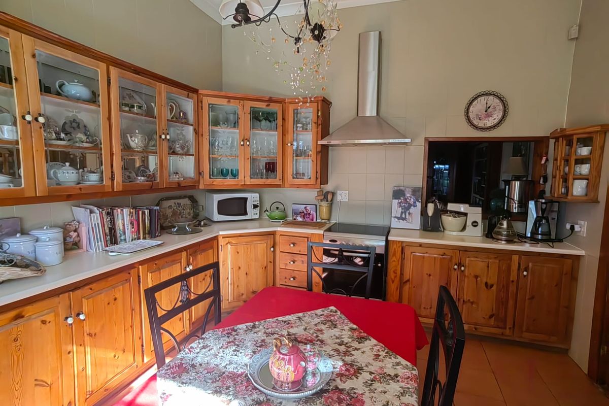 A traditional kitchen featuring timber cabinetry, glass-fronted display units, a stainless steel extractor fan, and a tiled splashback.