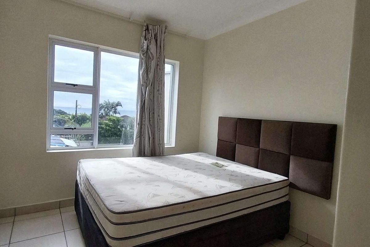 A bedroom featuring tiled flooring and a large aluminium window with natural light and exterior views.