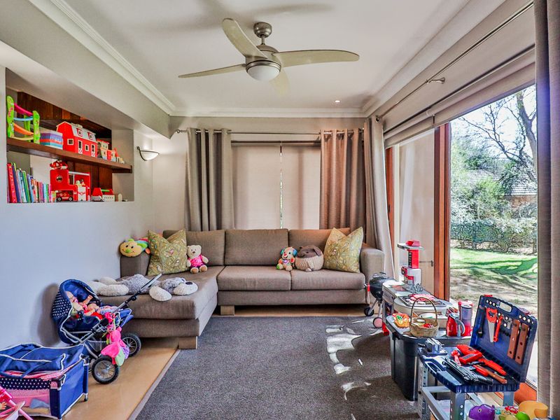 A comfortable living room featuring a ceiling fan, recessed shelving, and large sliding glass doors that provide natural light and garden access.