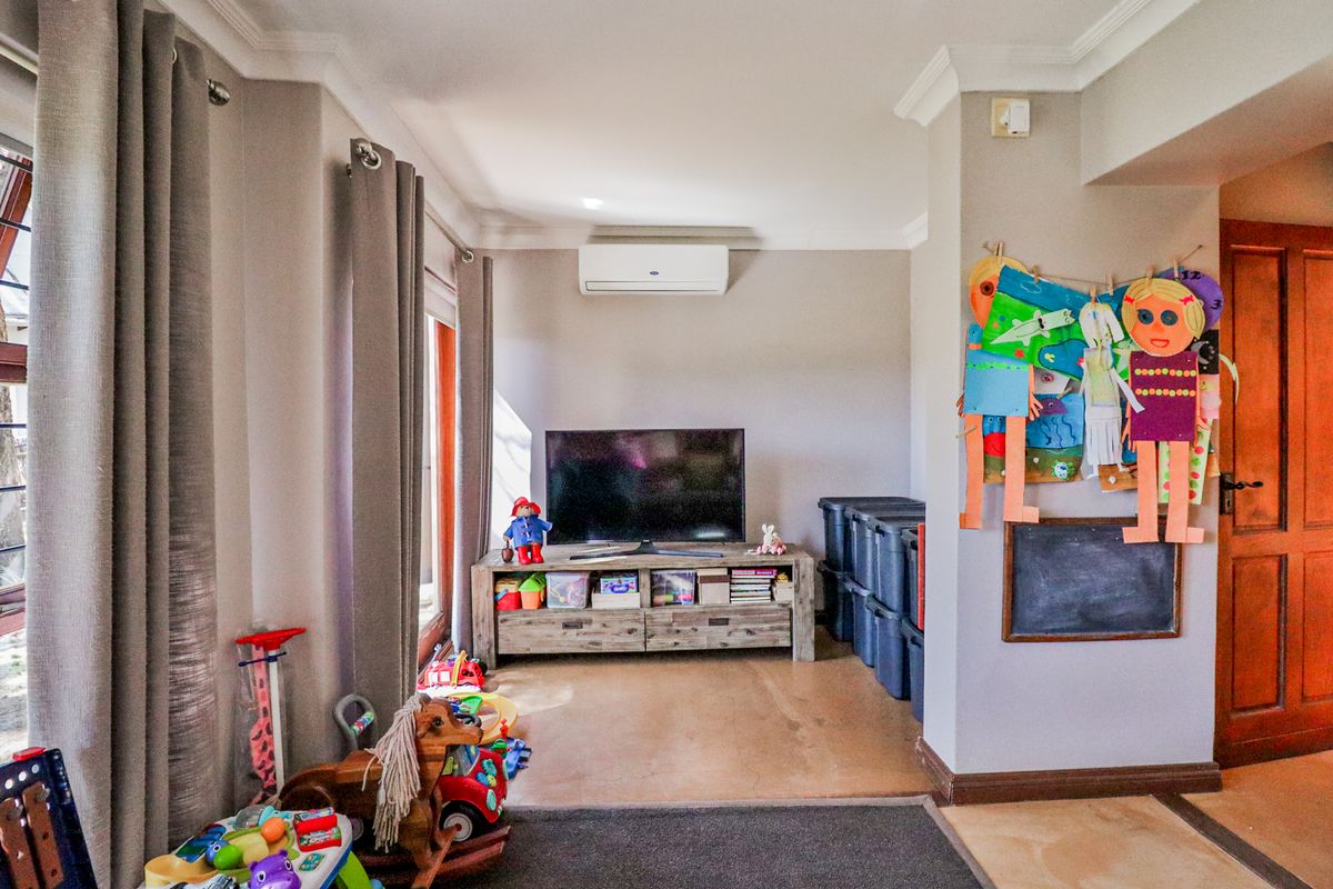 A living area featuring crown molding, a wall-mounted air conditioning unit, and a timber door, providing a functional space for family activities.