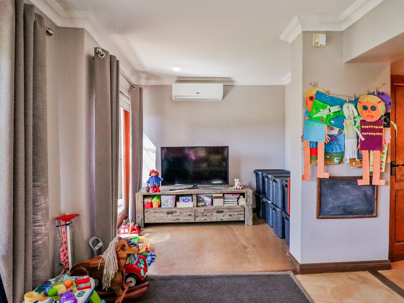 A living area featuring crown molding, a wall-mounted air conditioning unit, and a timber door, providing a functional space for family activities.