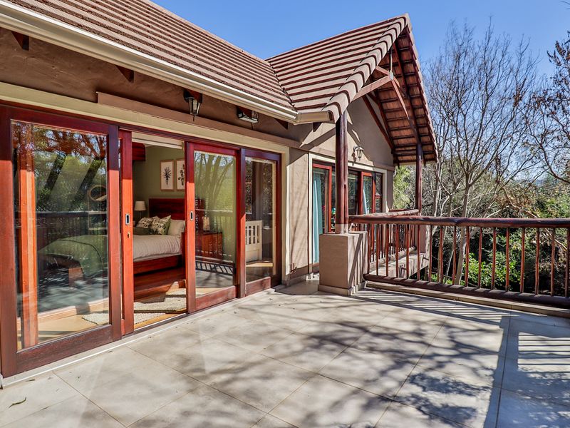 Spacious covered balcony featuring tiled flooring, timber sliding doors, and a timber balustrade, offering a seamless transition between indoor and outdoor living spaces.