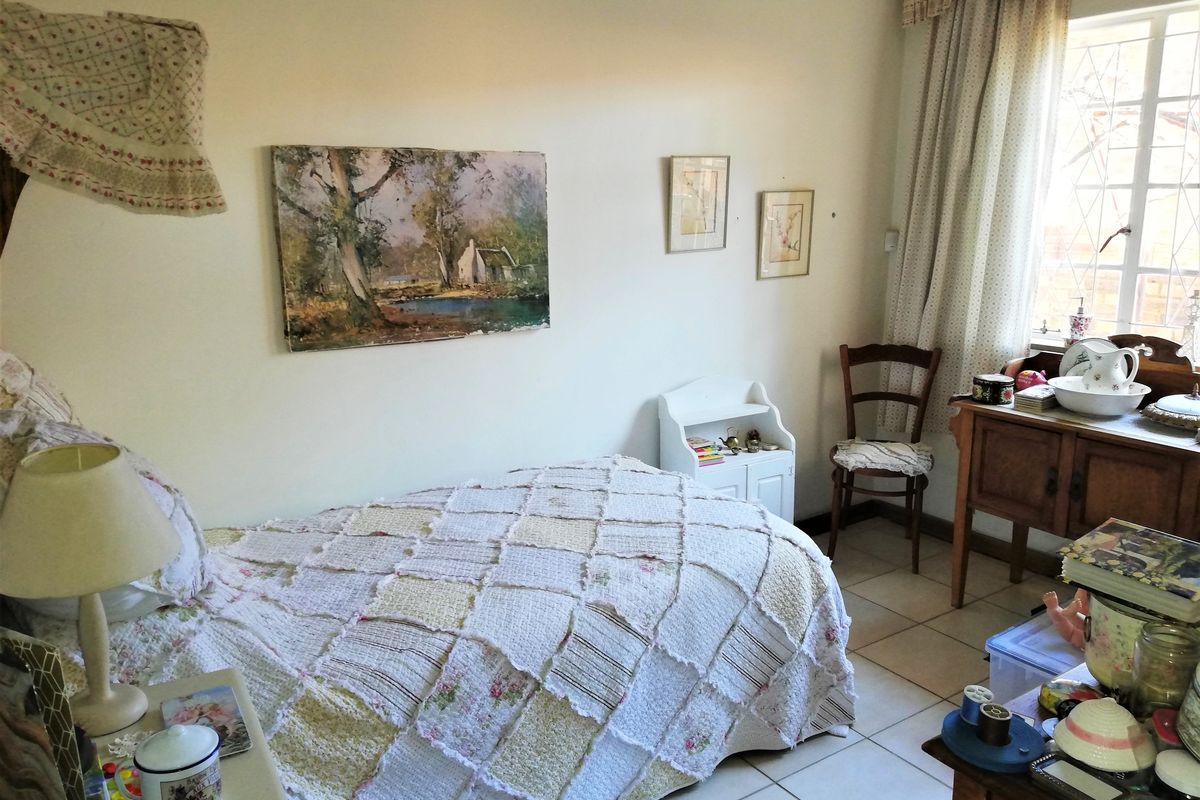 A bedroom featuring tiled flooring and a window fitted with security bars, offering a functional space with natural light.