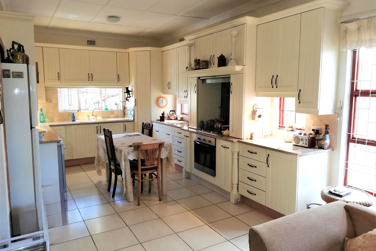 A spacious kitchen featuring cream-colored cabinetry, granite countertops, integrated oven, and tiled flooring, offering a functional layout with ample storage and workspace.