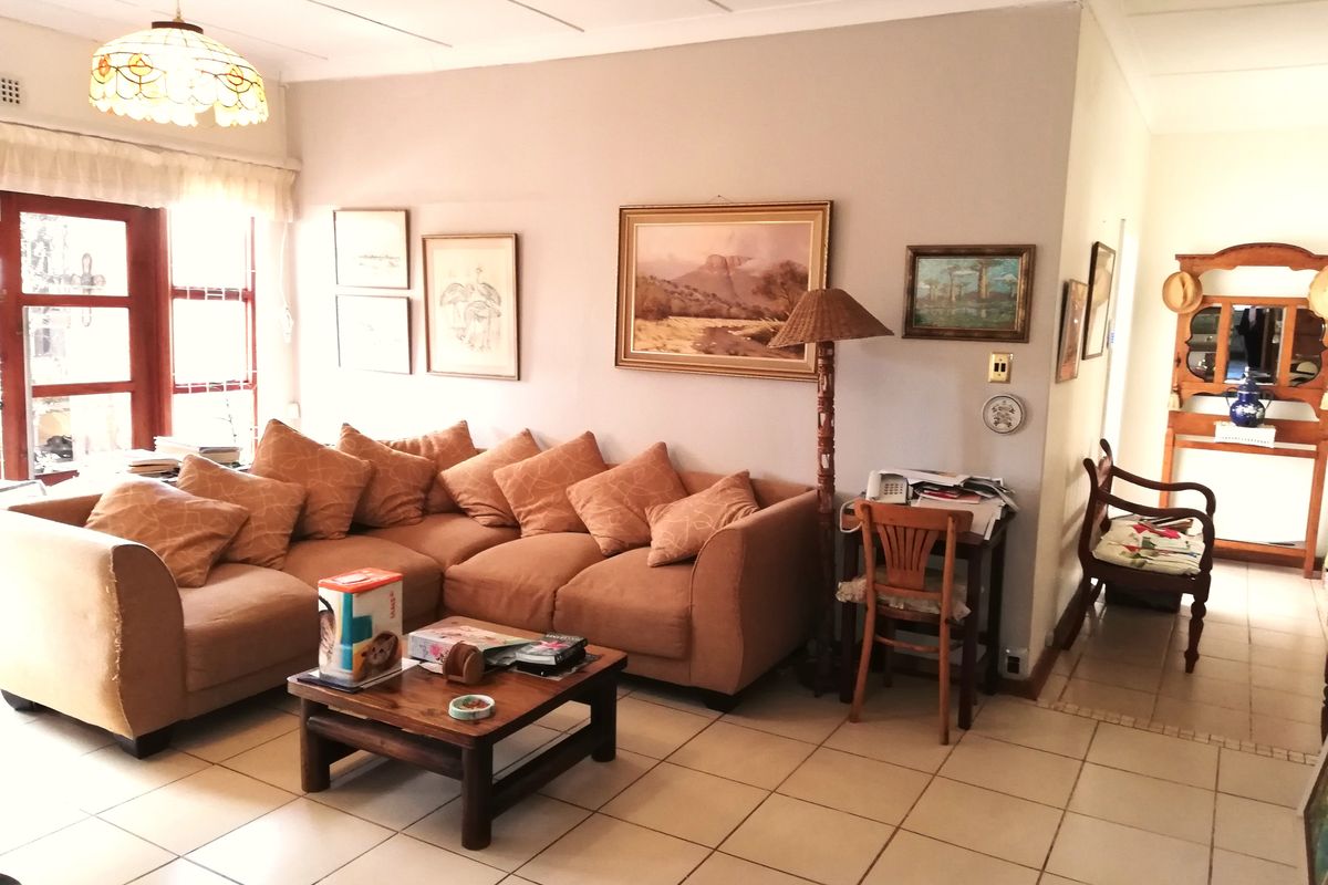 A comfortable living room featuring ceramic floor tiles, a coved ceiling, and a timber-framed glass door providing natural light.