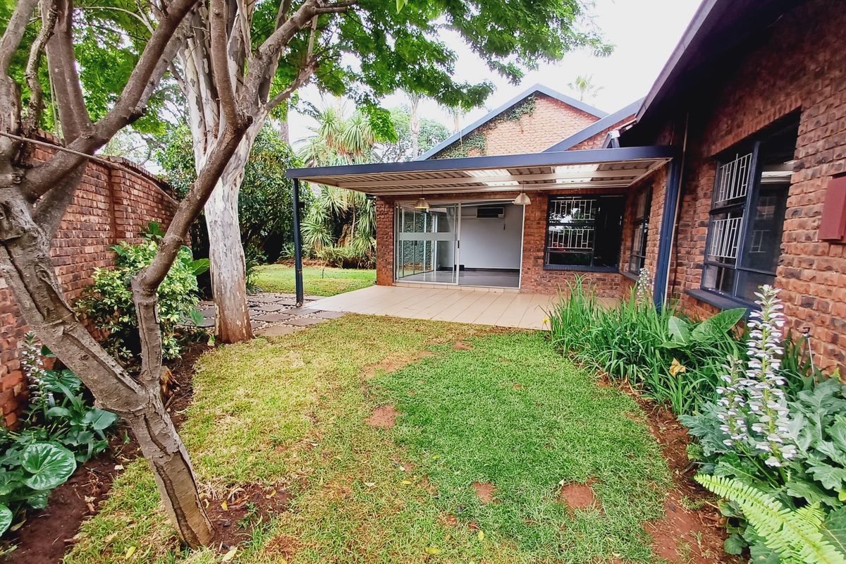 Rear view of the property featuring a covered patio with tiled flooring, brick exterior walls, and a private garden area.