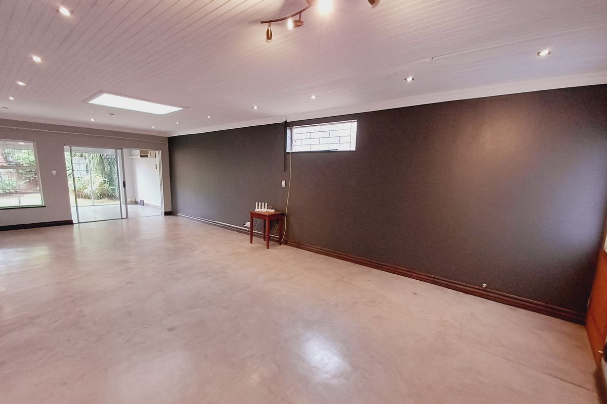 Spacious, open-plan living area featuring polished concrete floors, a skylight, recessed lighting, and large sliding doors leading to the garden.