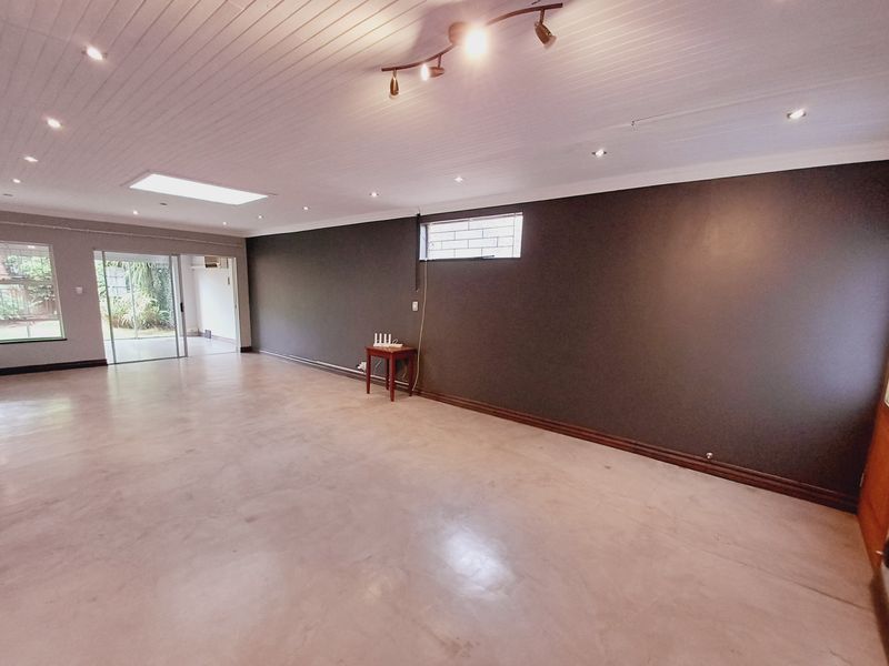 Spacious, open-plan living area featuring polished concrete floors, a skylight, recessed lighting, and large sliding doors leading to the garden.