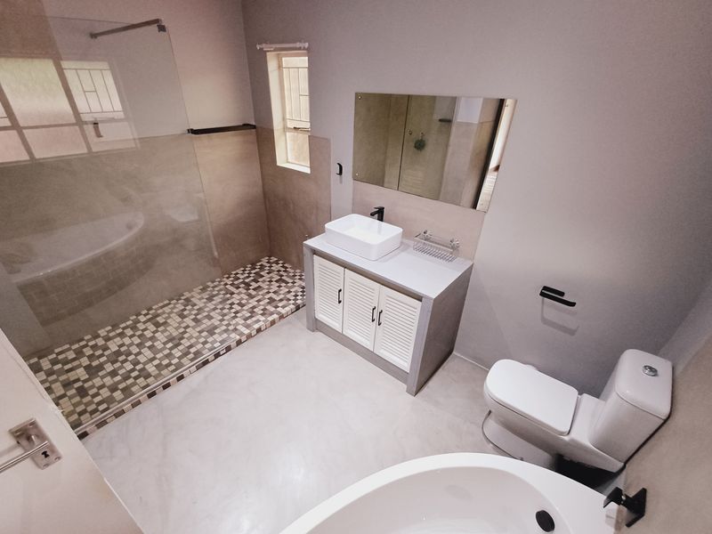 Modern bathroom featuring a walk-in shower with mosaic tiling, a vanity with vessel sink, a freestanding bathtub, and contemporary fixtures.