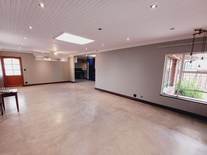 Spacious open-plan living area featuring polished concrete floors, a skylight, and recessed lighting, offering a versatile blank canvas for interior design.