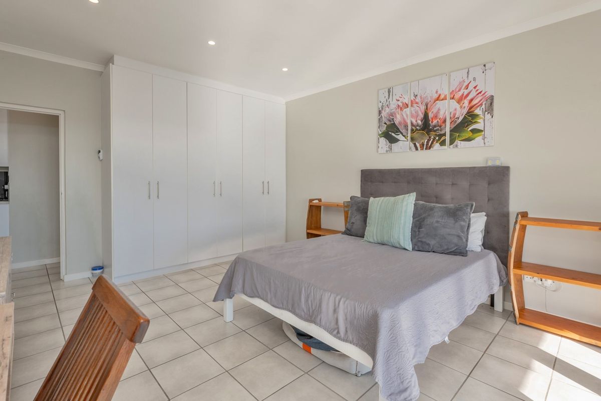 A well-maintained bedroom featuring neutral tiled flooring, ample built-in cupboard storage, and recessed ceiling lighting.