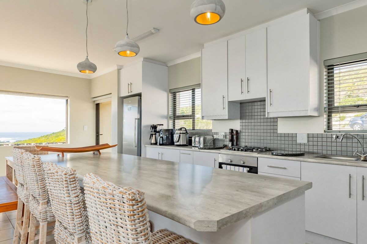 Modern kitchen featuring white cabinetry, stone-look countertops, tiled backsplash, built-in oven, gas hob, and a spacious breakfast island with pendant lighting.