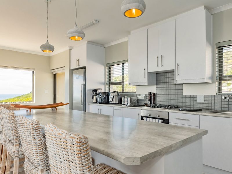 Modern kitchen featuring white cabinetry, stone-look countertops, tiled backsplash, built-in oven, gas hob, and a spacious breakfast island with pendant lighting.