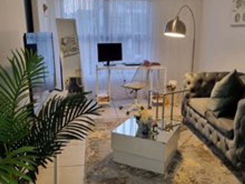 A compact living room featuring tiled flooring and a large window, providing a functional space for relaxation and home office use.