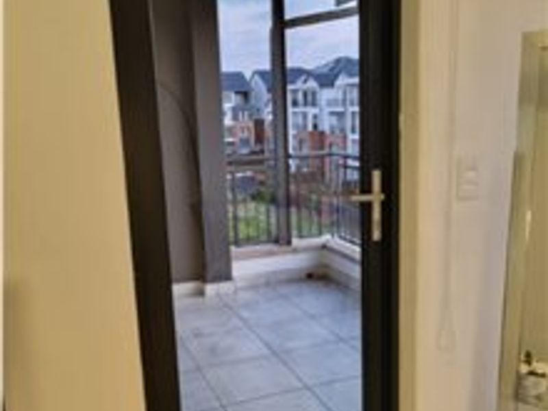 A view from an interior space looking out onto a tiled balcony with a metal balustrade and neighborhood views.