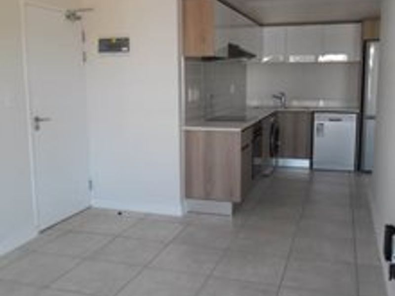 A clean, modern kitchen featuring built-in cabinetry, laminate countertops, and integrated appliances, set against neutral tiled flooring in an open-plan layout.