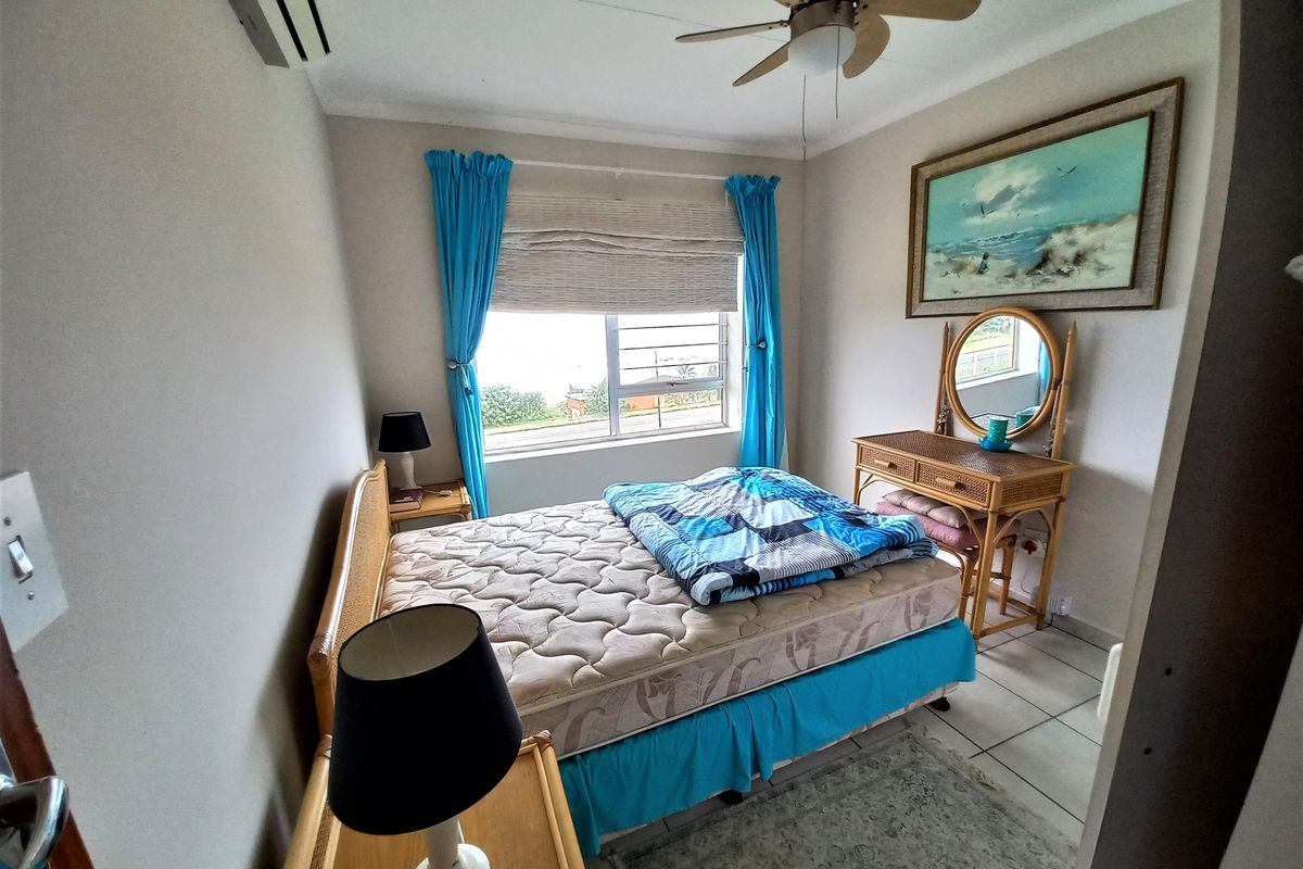 A functional bedroom featuring tiled flooring, a wall-mounted air conditioning unit, and a window with security bars.