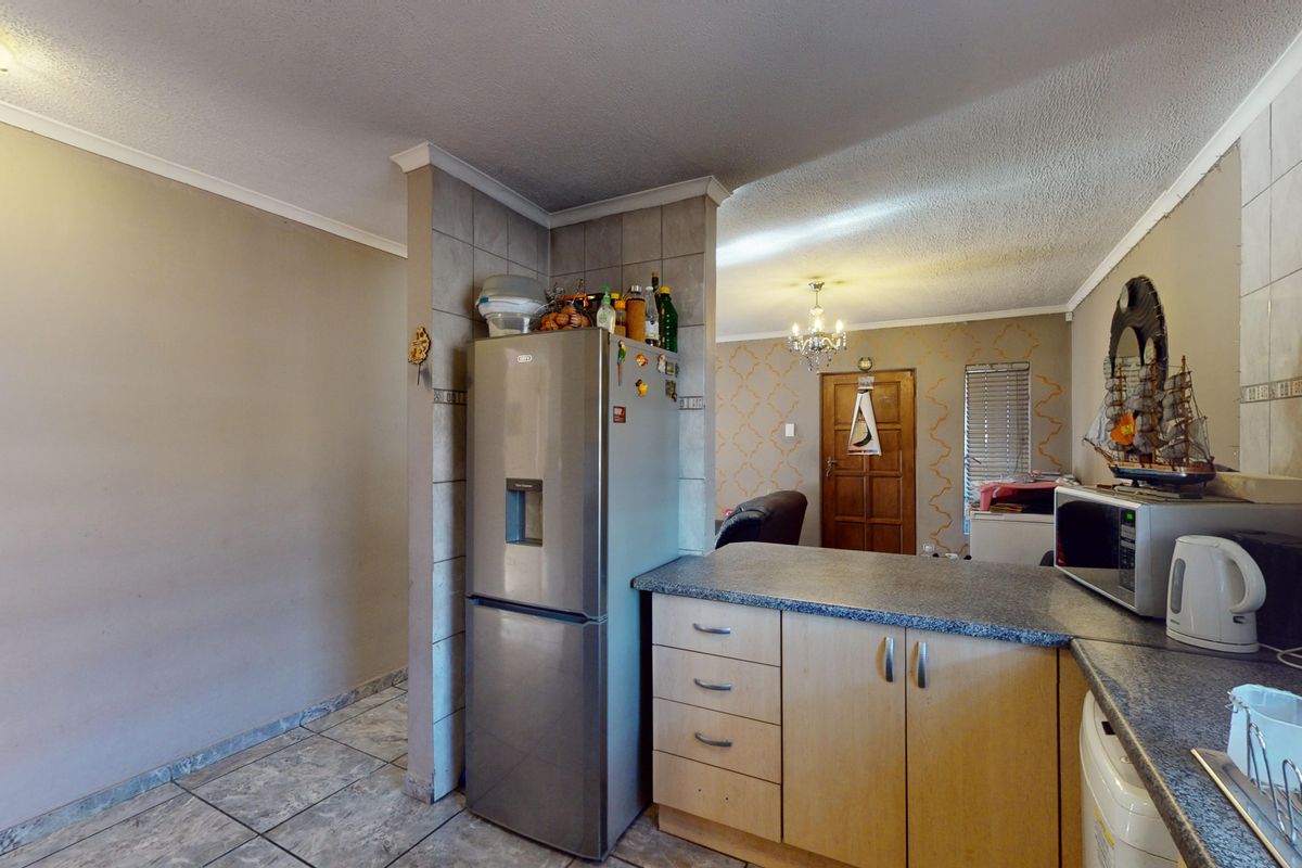 A functional kitchen area featuring tiled flooring, laminate cabinetry, and a granite-look countertop, offering a practical layout with potential for modern updates.