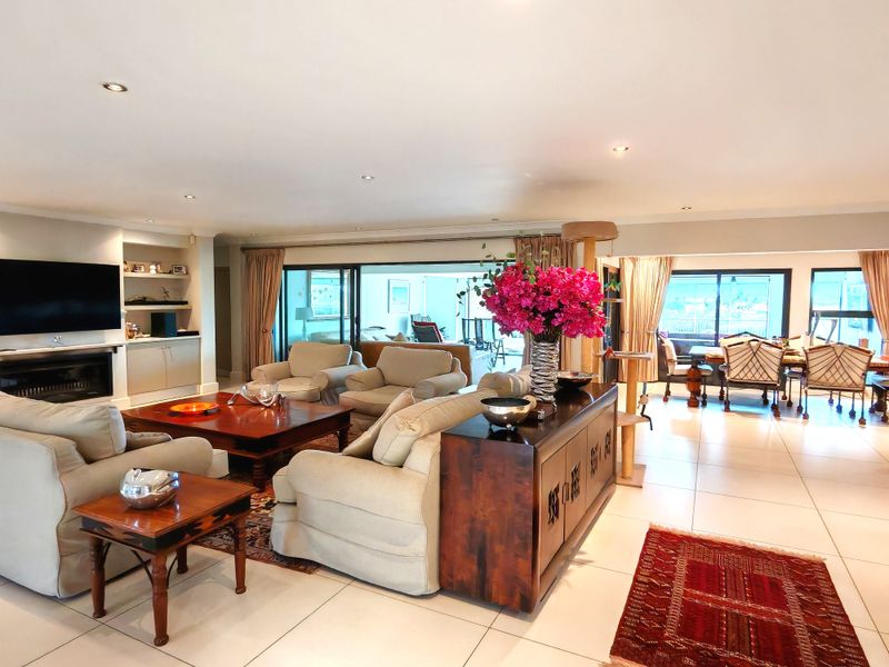 Spacious open-plan living and dining area featuring tiled floors, recessed lighting, a built-in fireplace, and large sliding doors leading to the outdoor space.