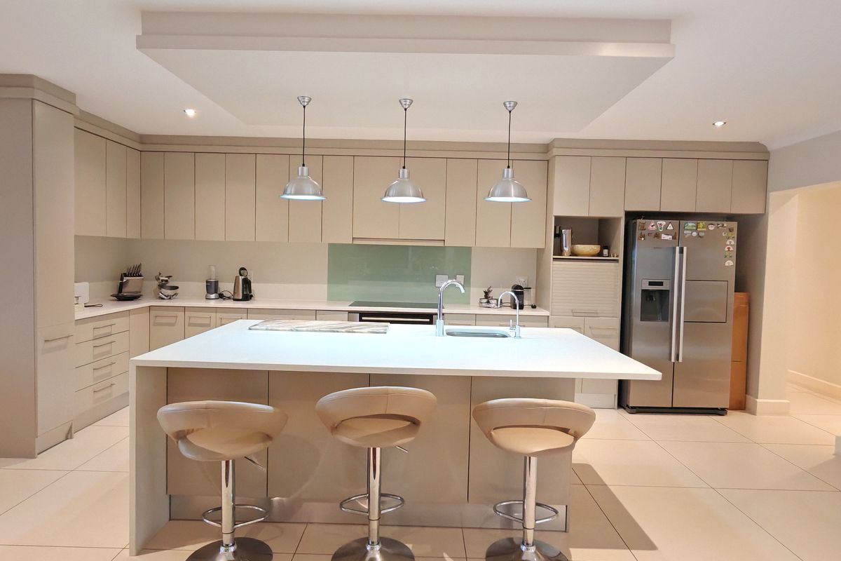 Modern, well-appointed kitchen featuring a large central island with quartz countertops, sleek cabinetry, integrated appliances, and stylish pendant lighting.