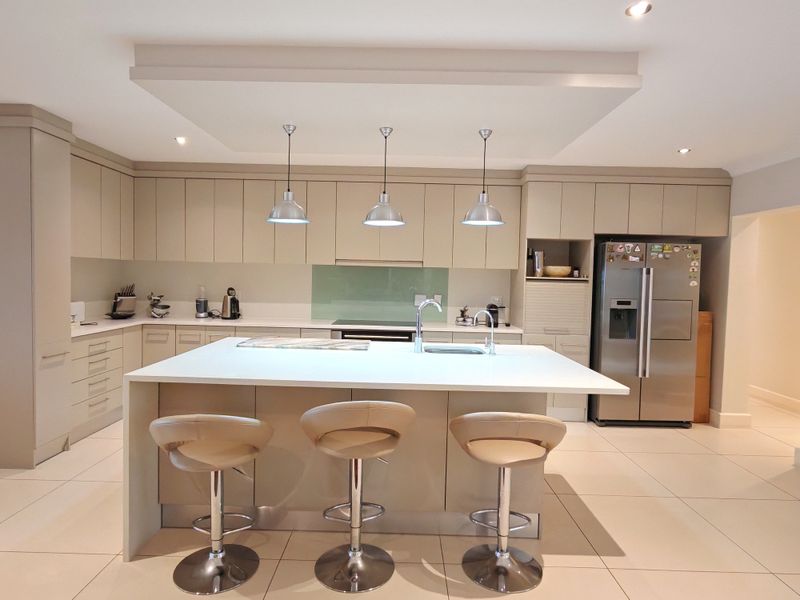 Modern, well-appointed kitchen featuring a large central island with quartz countertops, sleek cabinetry, integrated appliances, and stylish pendant lighting.