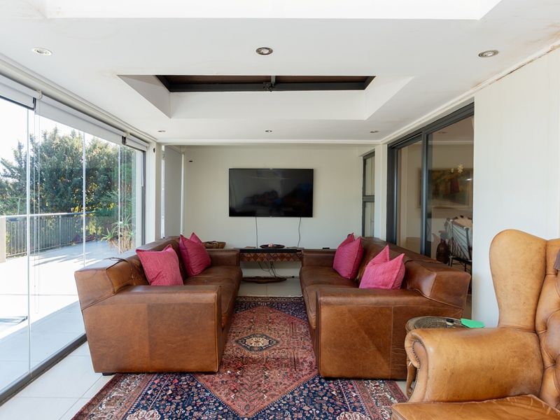 A bright living room featuring tiled flooring, a central skylight, recessed lighting, and large sliding glass doors that provide access to the outdoor area.